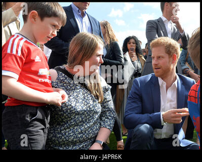 Prinz Harry spricht mit Lee Rigbys Frau Rebecca und seinem Sohn Jack (links, im roten Fußball oben) während einer Tee-Party im Buckingham-Palast veranstaltet von Prinz Harry und der Herzog und die Herzogin von Cambridge für die Kinder der Streitkräfte Männer und Frauen, die für ihr Land gestorben. Stockfoto