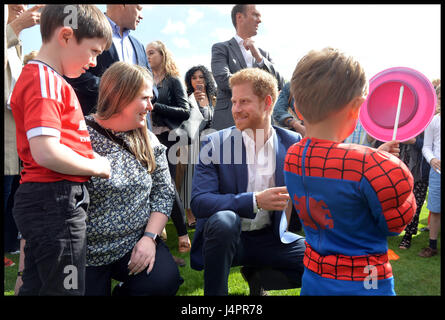 Prinz Harry spricht mit Lee Rigbys Frau Rebecca und seinem Sohn Jack (links, im roten Fußball oben) während einer Tee-Party im Buckingham-Palast veranstaltet von Prinz Harry und der Herzog und die Herzogin von Cambridge für die Kinder der Streitkräfte Männer und Frauen, die für ihr Land gestorben. Stockfoto