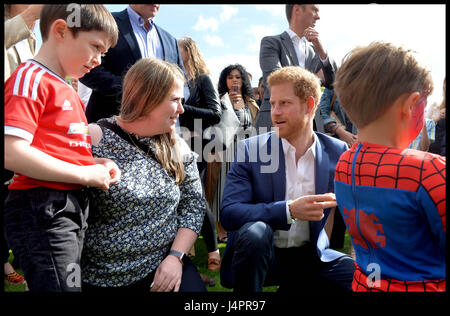 Prinz Harry spricht mit Lee Rigbys Frau Rebecca und seinem Sohn Jack (links, im roten Fußball oben) während einer Tee-Party im Buckingham-Palast veranstaltet von Prinz Harry und der Herzog und die Herzogin von Cambridge für die Kinder der Streitkräfte Männer und Frauen, die für ihr Land gestorben. Stockfoto