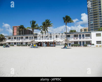 Sunny Isles Beach, USA - 22. März 2011: Monaco Motel oder Hotel direkt am Strand mit Sonnenschirmen und Gebäuden und Palmen Stockfoto