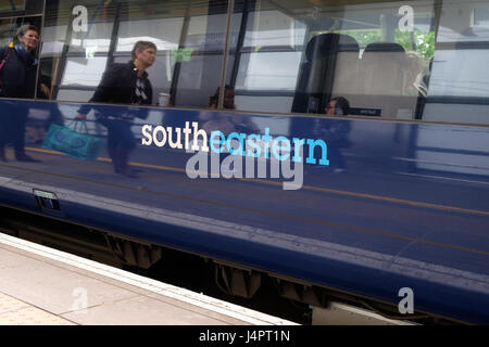 Südöstlicher Zug wartet auf Ashford International Station, Passanten Reflexion, Menschen, Logo im Zug, ashford, kent, großbritannien Stockfoto