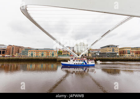 Newcastle, England - 16. April 2017: ein blau-weißes Kreuzfahrtschiff Unterquerung der gekippten Millennium Bridge an einem bewölkten Morgen in die Gateshead Stockfoto