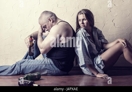 Junges Paar im Kampf gegen den Alkoholismus sitzen auf dem Boden von einem leeren Raum Stockfoto