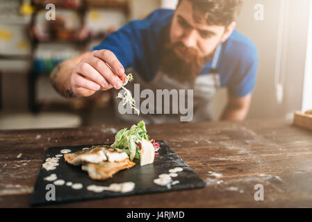 Koch mit Gemüse Gericht aus gebratenen Fisch auf Tablett aus Holz dekorieren. Frische gesunde Meeresfrüchte. Gourmet-dinner Stockfoto