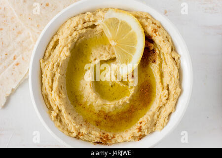 Hummus mit Gewürzen und Zitrone im selektiven Fokus Schüssel weiß Stockfoto