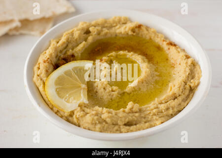Hummus mit Gewürzen und Zitrone im selektiven Fokus Schüssel weiß Stockfoto