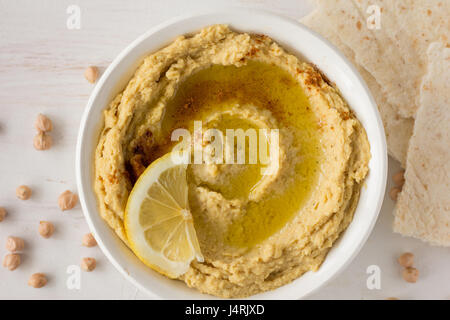 Hummus mit Gewürzen und Zitrone im selektiven Fokus Schüssel weiß Stockfoto