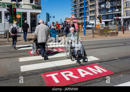 Gruppe der älteren Behinderten im Rollstuhl durchqueren Straße über Fußgängerüberweg / Zebrastreifen in der Stadt Stockfoto