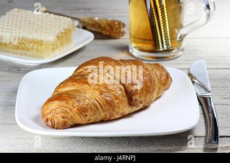 leckeres Frühstück mit schwarzem Tee, Croissant und Kamm Honig Stockfoto