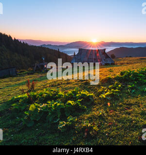 Schäfer-Haus im Hochgebirge. Orange Sunrice Glühen durch Sonnenlicht. Sommerzeit im Hochland Stockfoto