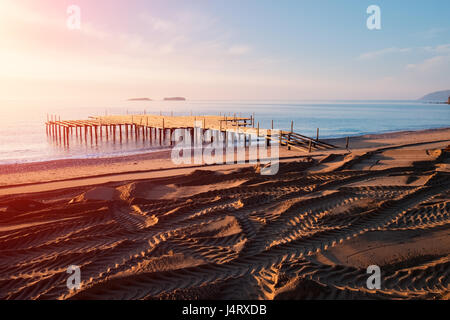 Installation der Sommer-Terrasse am Strand. Atemberaubenden Blick auf das Mittelmeer. Importierten Sand an einem steinigen Strand. Track von Rädern Stockfoto