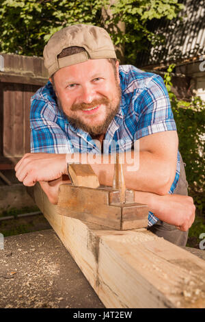 Carprnter Portrait mit Holzbrett und Flugzeug lächelnd auf natürlichen Hintergrund Stockfoto