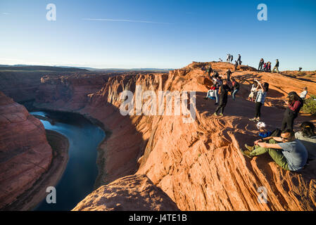 Touristen bewundern die Aussicht im Horseshoe Bend bei Sonnenuntergang mit dem Colorado River im Schatten, Arizona Stockfoto