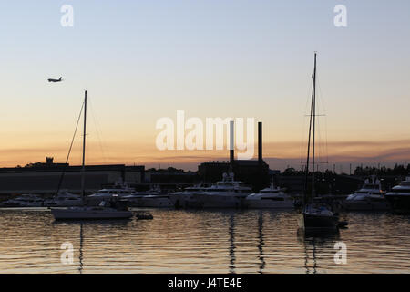 Ein Flugzeug fliegt über Sydneys Inner-West bei Sonnenuntergang von Rozelle Bay ersichtlich. Stockfoto