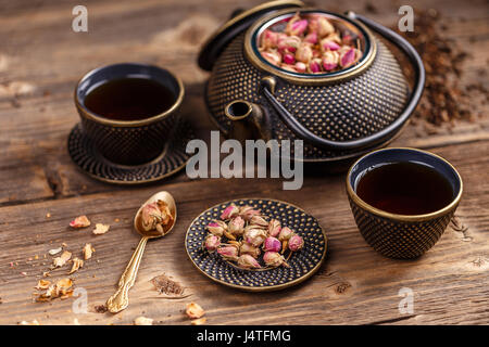 Teekanne und Teetassen mit trockenen Rosenknospen auf Vintage Holz-Hintergrund Stockfoto