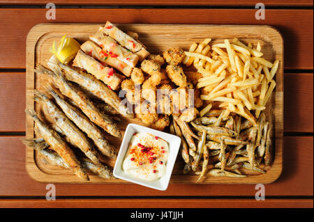 großes Holzbrett mit gebratenen Fush, Muscheln, Pommes frites serviert als Begleiter für Bier oder andere Getränke Alcool, Ansicht von oben Stockfoto