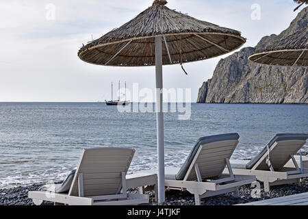 Parsols und Sonnenliegen auf Kamari Strand Kamari, Santorini, Griechenland Stockfoto