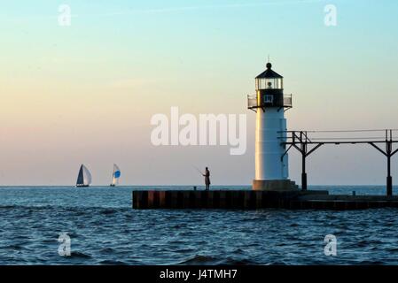 Ein einsamer Fischer bei Sonnenuntergang am Leuchtturm Pier in Saint Joseph, Lake Michigan. Stockfoto