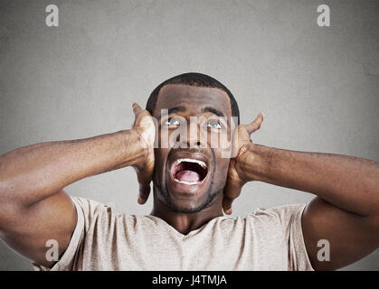 Closeup Portrait verärgert betonte jungen Mann drückte seinen Kopf, verrückt, schreien, seinen Verstand zu verlieren, vereinzelte graue Wand Hintergrund nachschlagen. Negati Stockfoto