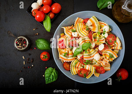 Nudeln, bunte Farfalle-Salat mit Tomaten, Mozzarella und Basilikum. Stockfoto