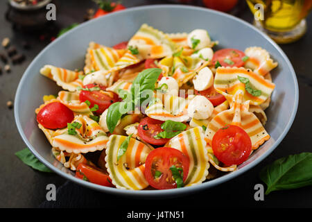 Nudeln, bunte Farfalle-Salat mit Tomaten, Mozzarella und Basilikum. Stockfoto