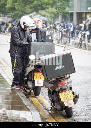 Ein Uber frisst Lebensmittel Lieferung Kurier bereitet sich auf Lebensmittel an einen Kunden aus einem Restaurant im Zentrum von London zu liefern. Uber isst konkurriert mit rivalisierenden Deliveroo Stockfoto