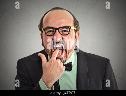 Portrait von angewidert Mann mit Finger im Mund sehr unzufrieden mit der Situation Dienst bereit zu Erbrechen werfen auf graue Wand Hintergrund isoliert. Menschlichen Stockfoto