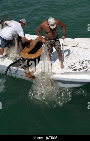 Angeln für Köder mit einer Besetzung net von einem kleinen Boot auf den Golf von Mexiko Florida USA Mann einen Fang kleiner Fische anlanden. April 2017 Stockfoto