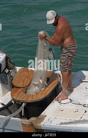 Angeln für Köder mit einer Besetzung net von einem kleinen Boot auf den Golf von Mexiko Florida USA Mann einen Fang kleiner Fische anlanden. April 2017 Stockfoto