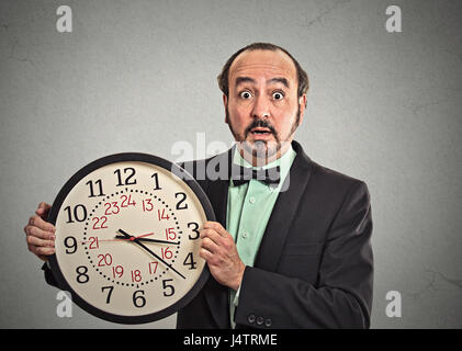 Porträt überrascht Geschäftsmann im Anzug Wand Uhr isoliert graue Wand Hintergrund halten. Wettlauf gegen die Zeit, Zeit vergeht, running out of Time, keine tim Stockfoto