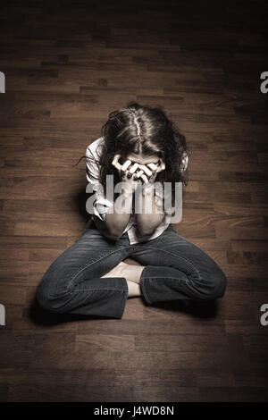 Traurige Frau sitzt alleine in einem leeren Raum Stockfoto
