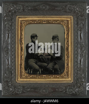Ein Foto von zwei nicht identifizierten Unions-Soldaten aus dem Amerikanischen Bürgerkrieg, die um 1863 Whiskey tranken und Karten spielten, um die Gelegenheitsmomente der Soldaten während des Konflikts festzuhalten. Stockfoto