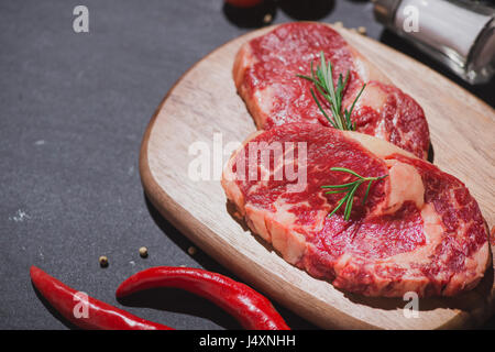 Rohes Rindfleisch auf ein Schneidebrett mit Gewürzen und Zutaten zum Kochen. Stockfoto