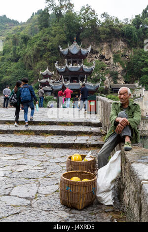 Zhenyuan, Guizhou, China.  Pomelo-Anbieter auf Wand Zhusheng Brücke über den Fluss Wuyang sitzen. Stockfoto