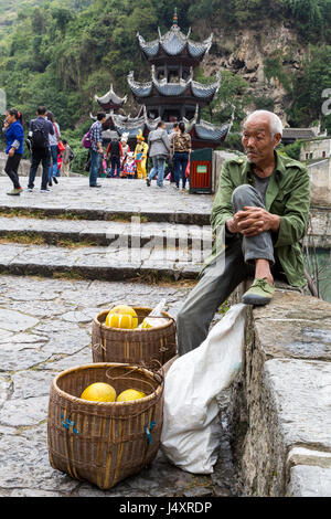 Zhenyuan, Guizhou, China.  Pomelo-Anbieter auf Wand Zhusheng Brücke über den Fluss Wuyang sitzen. Stockfoto