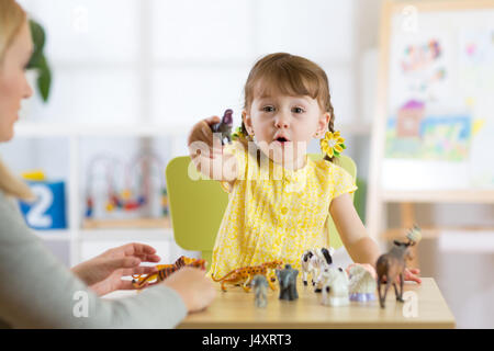 Glückliches Kind Mädchen. Lächelndes Kind Kleinkind spielt tierisches Spielzeug zu Hause oder im kindergarten Stockfoto