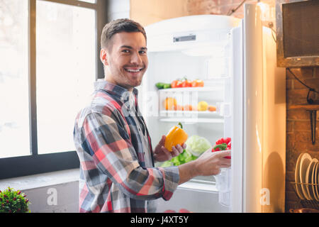 Junger Mann Vegan Einkäufe gesunde Produkte in Kühlschrank stellen Stockfoto