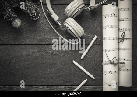 Draufsicht Weihnachten Musik Notizpapier mit Weihnachtsdekoration und Kopfhörer auf Holztisch Hintergrund. Erschaffen Sie dieser Hinweis Notenpapier selbst. Stockfoto