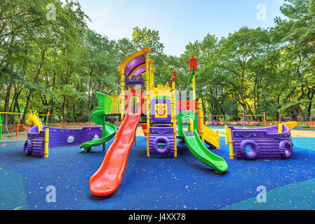 Kinderspielplatz am Hof Aktivitäten im öffentlichen Park, umgeben von grünen Bäumen im Sonnenlicht am Morgen. Stockfoto