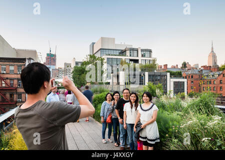 Erhöhten Exterieur aus der Highline mit asiatischen Touristengruppe. 500 West 21st Street, New York, Vereinigte Staaten. Architekt: Kohn Pedersen Fox Nikotinabhängigkeit Stockfoto