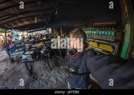 Tourist unter Selfie auf Straße Garküche in Indien Busbahnhof unterwegs. Fisch-Auge Ansicht mit indischen Süßigkeiten im Vordergrund. Stockfoto