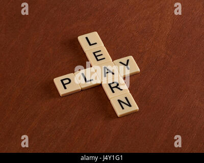 Kreuzworträtsel mit Worten lernen und spielen. Bildungskonzept. Elfenbein Fliesen mit Großbuchstaben auf Mahagoni Brett. Stockfoto