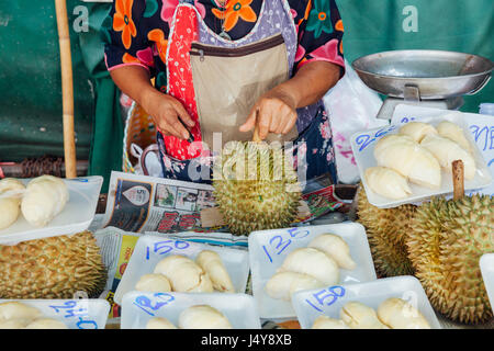 CHIANG MAI, THAILAND - 24 AUGUST: Frau schneidet Durian zum Verkauf auf dem Markt am 23. August 2016 in Chiang Mai, Thailand. Stockfoto