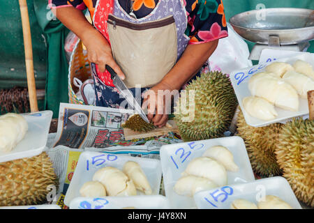CHIANG MAI, THAILAND - 24 AUGUST: Frau schneidet Durian zum Verkauf auf dem Markt am 23. August 2016 in Chiang Mai, Thailand. Stockfoto