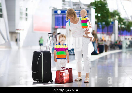 Familie am Flughafen vor dem Flug. Mutter und Kinder an Bord am Abflug-Gate des modernen internationalen Terminals warten. Reisen und fliegen mit childr Stockfoto