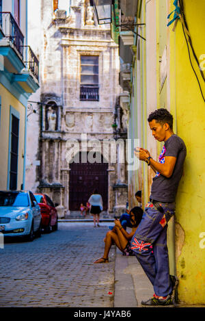 Jugendliche Surfen im Internet mit ihrem Handy in einer schäbigen Straße in Havanna Kuba Stockfoto