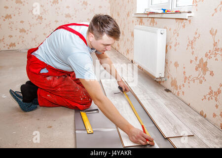 junge Handwerker installieren Holzboden im neuen Haus Stockfoto