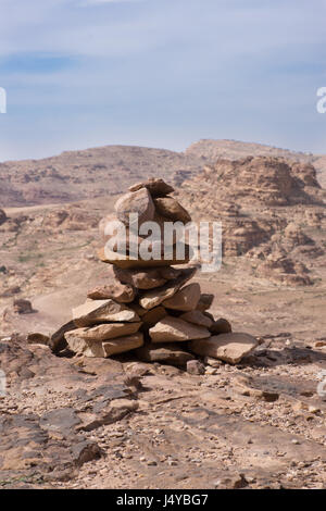 Nahaufnahme von einem Steinhaufen am Rand einer Klippe in der Nähe von Petra Jordan. Schroffe Berge und hellblauen bewölkten Himmel ist im Hintergrund. Stockfoto