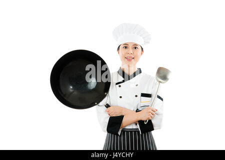 schöne Köchin mit Wok und Spachtel Werkzeuge mit Hände gekreuzt vor weißer Wand Hintergrund mit Exemplar steht. Beruf und indus Stockfoto