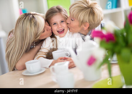 Süßes Mädchen Kuss von ihrer Mutter und Großmutter erhalten Stockfoto